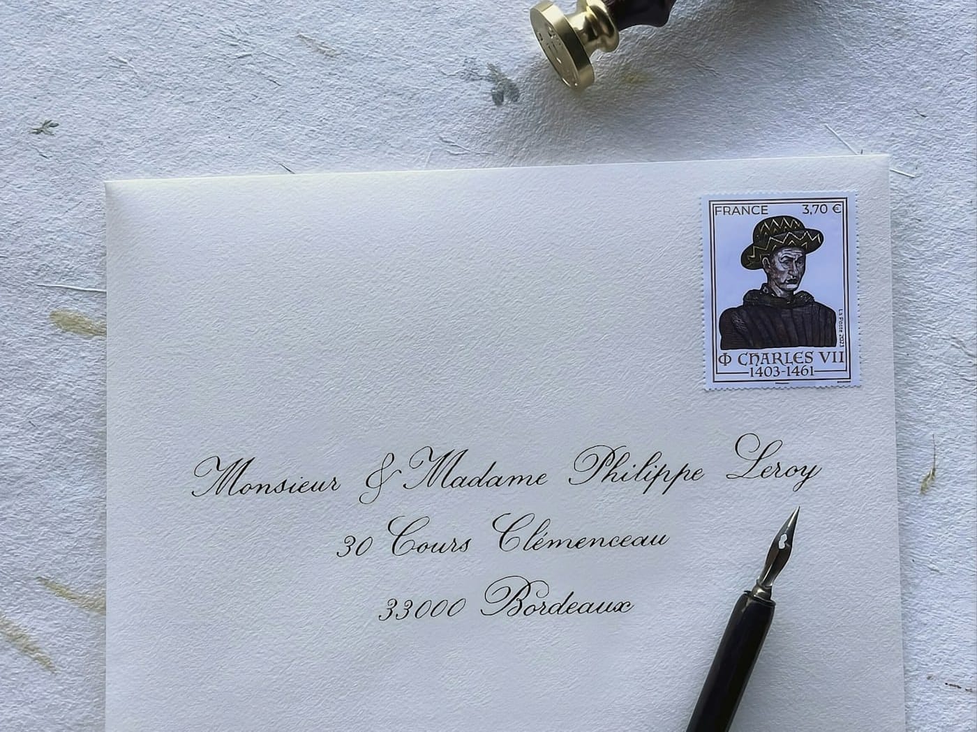 A hand-calligraphed envelope with a French stamp and a dip pen, addressed to a couple in Bordeaux