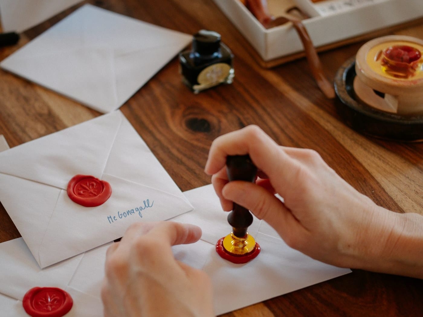 Hands pressing red wax seals onto white wedding envelopes